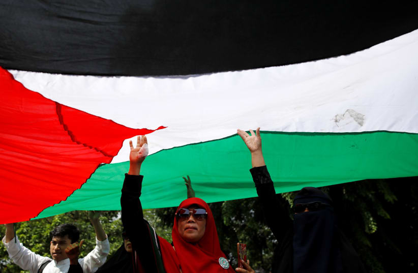 People hold up the Palestinian flag during a protest by Muslim groups to condemn Washington's decision to recognize Jerusalem as Israel's capital outside the U.S. embassy in Jakarta, Indonesia December 8, 2017.  (photo credit: DARREN WHITESIDE / REUTERS)