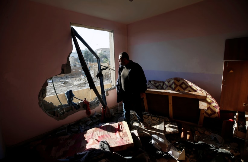 A Palestinian man looks at a nearby militant target in his apartment that was damaged in an Israeli airstrike, in the northern Gaza Strip December 9, 2017. (photo credit: MOHAMMED SALEM/ REUTERS)