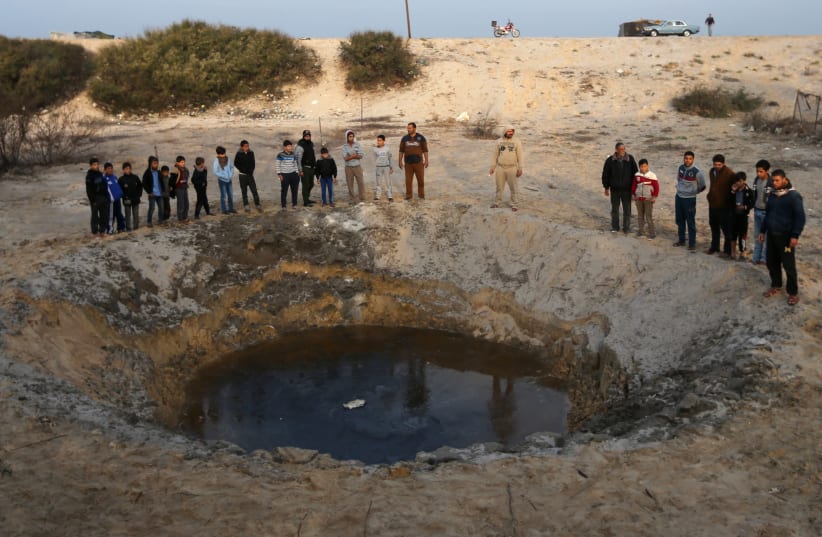 Palestinians gather at the site of an Israeli airstrike in the southern Gaza Strip December 13, 2017. (photo credit: REUTERS)