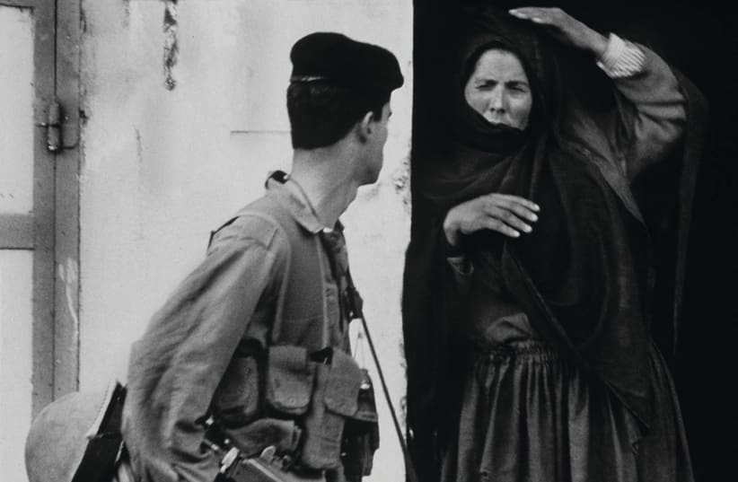 A PALESTINIAN woman and an Israeli soldier exchange glances as he passes her house in Rafah, at the southernmost part of the Gaza Strip, 10 days after the start of the first intifada in 1987 (photo credit: REUTERS)