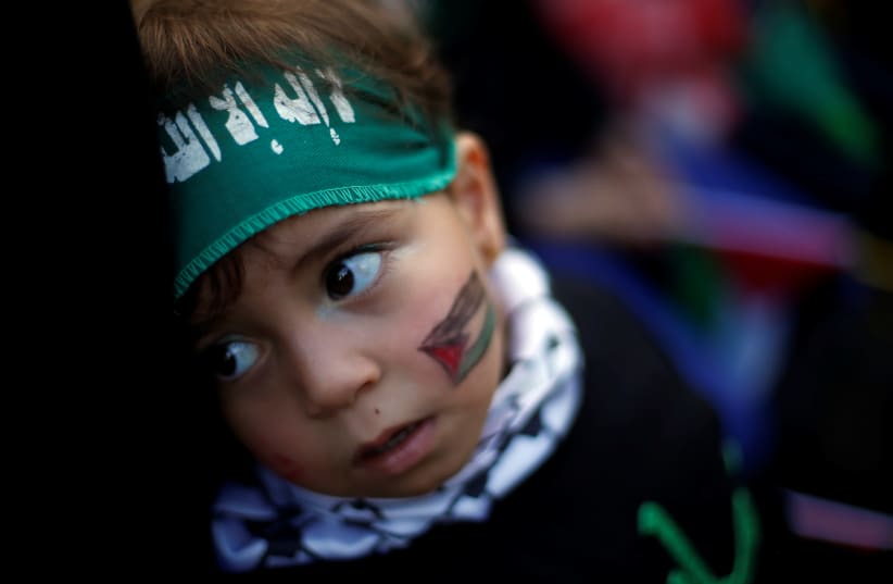 A Palestinian child wearing Hamas headband takes part in a rally marking the 30th anniversary of Hamas' founding, in Gaza City December 14, 2017 (photo credit: SUHAIB SALEM / REUTERS)