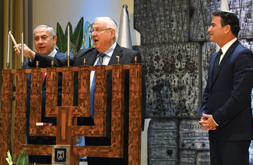 PRESIDENT REUVEN RIVLIN lights the second Hanukka candle in the presence of Prime Minister Benjamin Netanyahu and Mossad chief Yossi Cohen at an event honoring outstanding Mossad personnel. (photo credit: KOBI GIDEON/GPO)