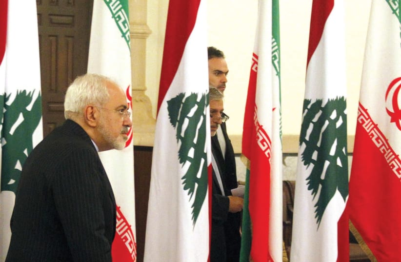 IRANIAN FOREIGN Minister Mohammad Javad Zarif walks near Lebanese and Iranian flags upon his arrival at the Government Palace in Beirut in 2015.  (photo credit: REUTERS)