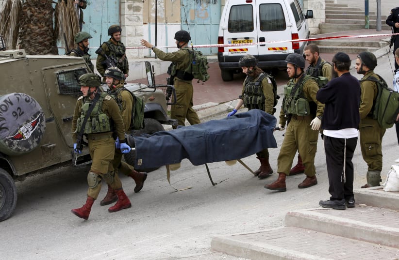 Israeli soldiers carry the dead body of one of two Palestinians, whom the Israeli military said were shot dead by Israeli troops after they attacked an Israeli soldier, in Tal Rumaida in the West Bank city of Hebron March 24, 2016.  (photo credit: REUTERS)