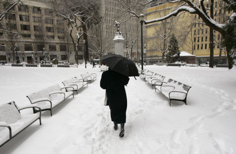 A pedestrian walks through a snow covered park in downtown Portland, Oregon. (photo credit: REUTERS)