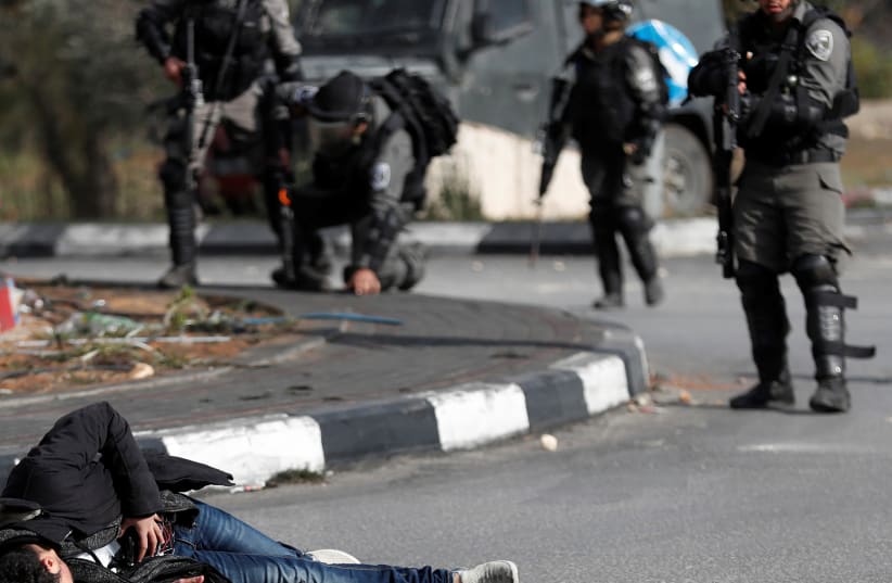 Israeli border policemen stand away after shooting a Palestinian man with a knife and what looks like an explosive belt near Ramallah (photo credit: GORAN TOMASEVIC/REUTERS)