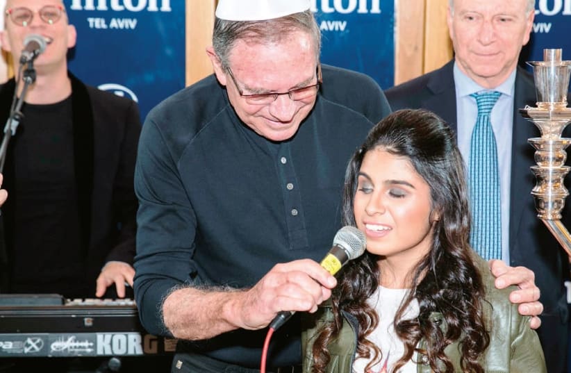 VARIETY ISRAEL chairman Ori Slonim holds the microphone for singer Eden Taharany at last week’s Tel Aviv Hilton Hanukka party. (photo credit: VARIETY ISRAEL)