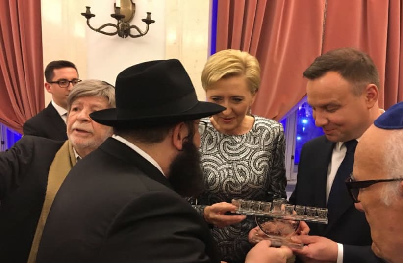 Chabad emissary Rabbi Szalom Ber Stambler presents Polish President Andrzej Duda and his wife Agata Kornhauser-Duda with a menorah at a Hanukka event at the palace. (photo credit: EWA SZMAL)
