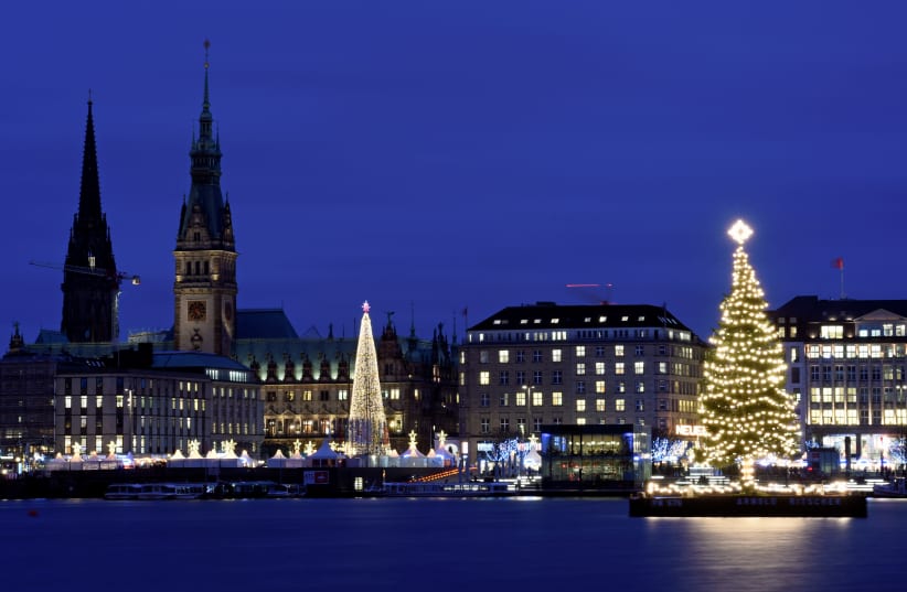 An illuminated Christmas tree on the Alster river shines in front of the Christmas market in Hamburg, Germany (photo credit: FABIAN BIMMER / REUTERS)