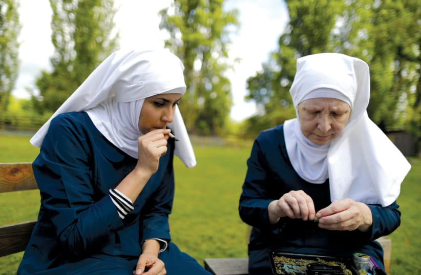 CALIFORNIA ‘WEED NUN’ Christine Meeusen (right), and India Delgado, who goes by the name Sister Eevee, smoke a joint at Sisters of the Valley near Merced, California (photo credit: REUTERS/LUCY NICHOLSON)