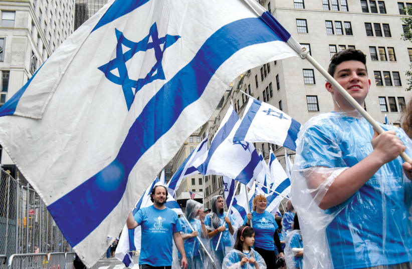 American Jews marching in New York with Israeli flags. How can we bridge the divide between Israel and the Diaspora? (photo credit: REUTERS)