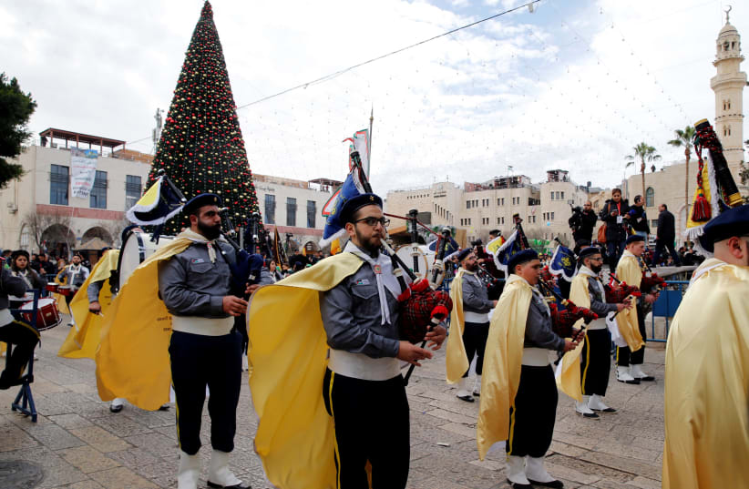 A Palestinian marching band takes part in a Christmas parade outside the Church of the Nativity in Bethlehem, December 2017 (photo credit: AMMAR AWAD / REUTERS)