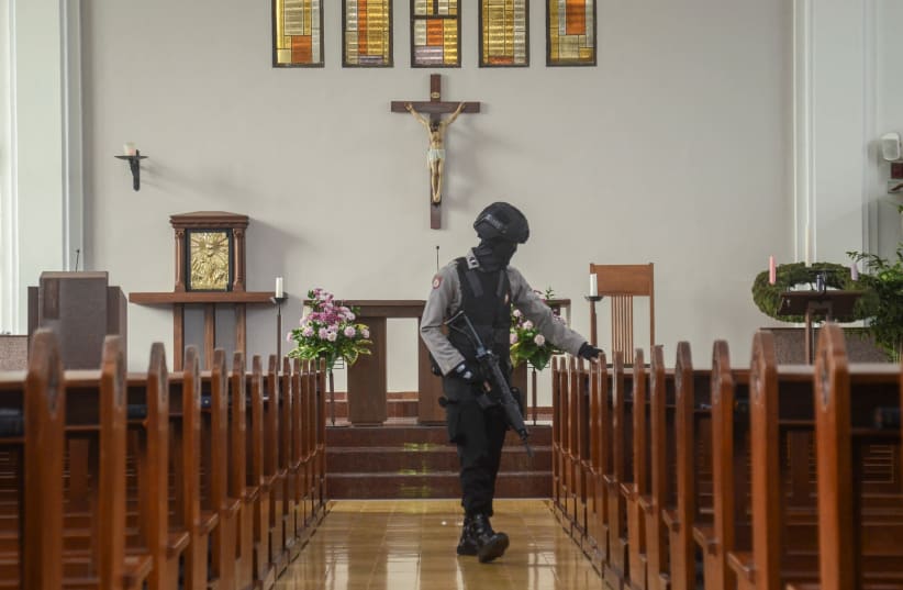 An Indonesian bomb squad policeman holds a rifle as he examines a church before Christmas mass prayer in Bandung, Indonesia, December 23, 2017 in this photo taken by Antara Foto. Picture taken December 23, 2017 (photo credit: ANTARA FOTO/RAISAN AL FARISI/VIA REUTERS)