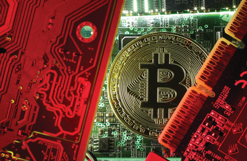  A coin representing the bitcoin cryptocurrency is seen on computer circuit boards in this illustrative picture (photo credit: REUTERS)