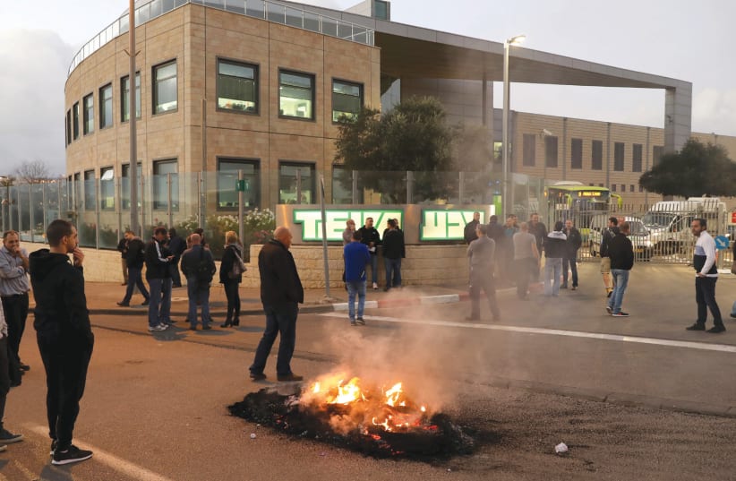 People protest outside a Teva Pharmaceutical Industries facility in Jerusalem on December 14 (photo credit: AMMAR AWAD/REUTERS)
