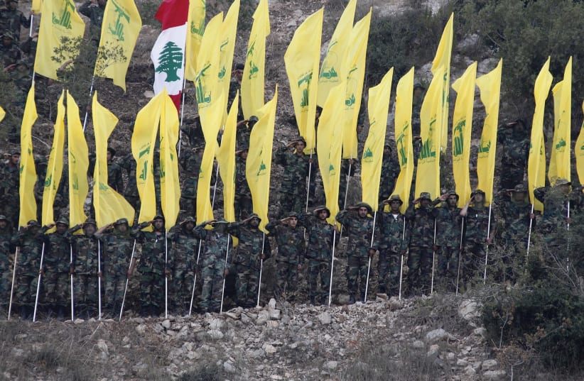 HEZBOLLAH MEMBERS wave Hezbollah and Lebanese flags during a 2015 rally in southern Lebanon marking the anniversary of the end of the terrorist organization’s 2006 war with Israel.  (photo credit: AZIZ TAHER/REUTERS)