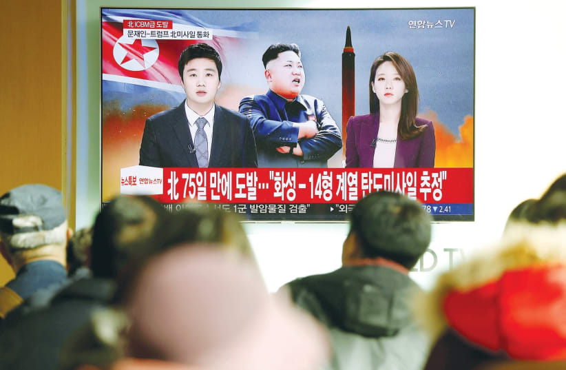 PEOPLE IN SEOUL watch a TV news report on North Korea’s launch of an ICBM that landed close to Japan last November (photo credit: KIM HONG/ REUTERS)