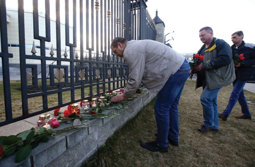 MEN LAY FLOWERS to commemorate victims of a blast in the St.Petersburg metro.  (photo credit: REUTERS)