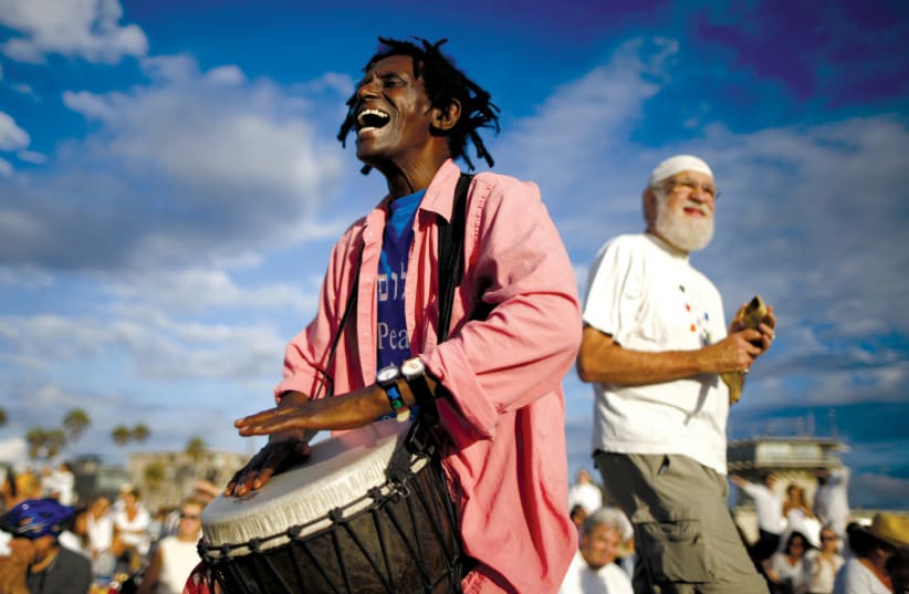 A MAN plays a drum during the Nashuva Spiritual Community’s Rosh Hashana celebration in Los Angeles in 2015. As Jews take part in the Tashlich prayer, bread crumbs are tossed into the waters to symbolically cast away sins (photo credit: LUCY NICHOLSON / REUTERS)