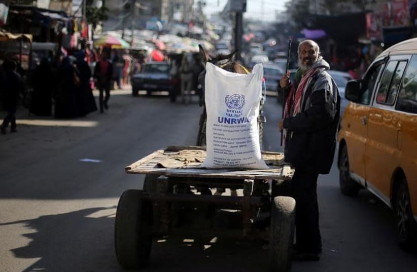 A Palestinian man stands next to a cart carrying a flour sack distributed by the United Nations Relief and Works Agency (UNRWA) in Khan Younis refugee camp in the southern Gaza Strip January 3, 2018 (photo credit: REUTERS/IBRAHEEM ABU MUSTAFA)