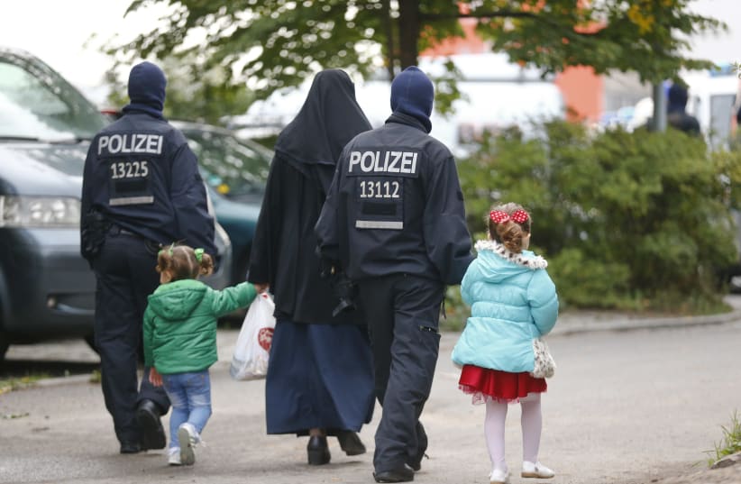 German security forces walk with a Muslim family outside a mosque in Berlin (photo credit: HANNIBAL HANSCHKE/REUTERS)
