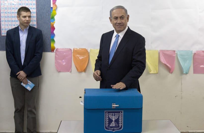Prime Minister Benjamin Netanyahu casts his ballot for the parliamentary election as his son Yair stands behind him at a polling station in Jerusalem March 17, 2015. (photo credit: REUTERS/SEBASTIAN SCHEINER/POOL)