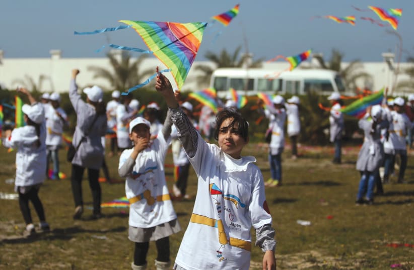 PALESTINIAN SCHOOLGIRLS fly kites to show solidarity with the Japanese people during an event organized by UNRWA to mark the anniversary of the March 11, 2011 earthquake and tsunami, in Khan Yunis in the southern Gaza Strip, in 2017. (photo credit: IBRAHEEM ABU MUSTAFA / REUTERS)