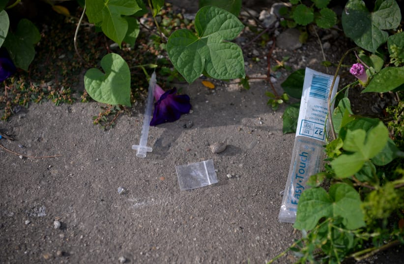 A needle used for shooting heroin and other opioids and an empty bag litter the ground in the Kensington section of Philadelphia, Pennsylvania, U.S. October 26, 2017. (photo credit: REUTERS/CHARLES MOSTOLLER)