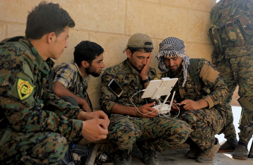  Members of the Syrian Democratic Forces control the monitor of their drone at their advanced position in a a district of Raqqa, Syria.  (photo credit: REUTERS)