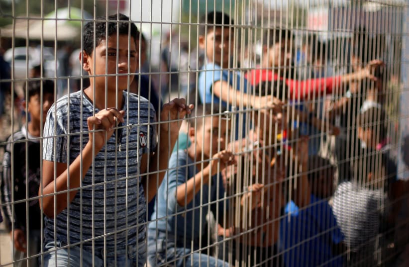 Palestinian boys stand by a fence at the Erez Crossing, October 2017 (photo credit: MOHAMMED SALEM/ REUTERS)