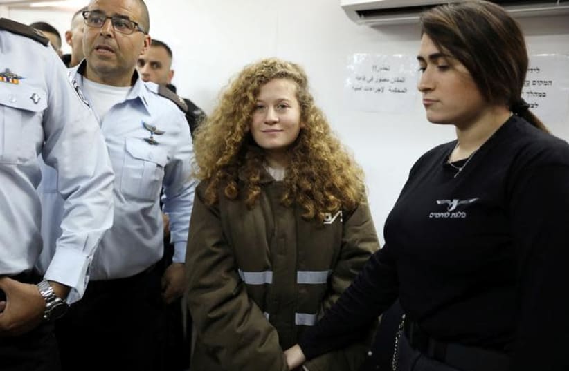  Palestinian teen Ahed Tamimi enters a military courtroom escorted by Israeli security personnel at Ofer Prison, near the West Bank city of Ramallah, January 15, 2018. (REUTERS/Ammar Awad) (photo credit: AMMAR AWAD / REUTERS)