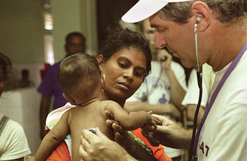 Le professeur Eli Schwartz de Tel Hashomer, spécialiste mondial des maladies tropicales, traite un enfant au Sri Lanka après le tsunami de 2004 (photo credit: Courtesy)