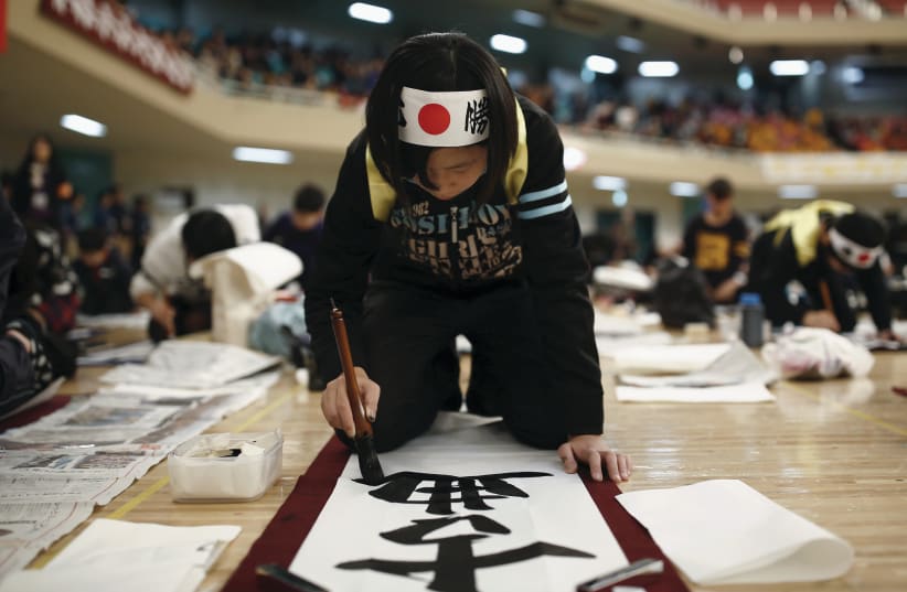 A GIRL participates in a calligraphy contest in Tokyo in 2016 (photo credit: THOMAS PETER/REUTERS)