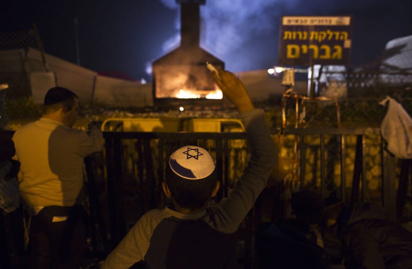 A Jewish worshipper throws candles into a fire during an annual pilgrimage to the gravesite of Rabbi Yisrael Abuhatzeira, a Moroccan-born sage and kabbalist also known as the Baba Sali. (photo credit: REUTERS)