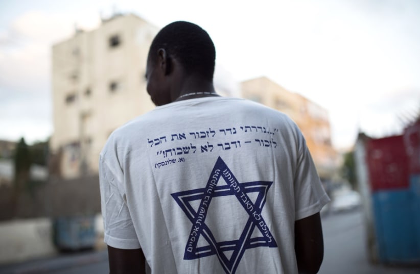 An African refugee in south Tel Aviv wears a T-shirt with a Hebrew phrase referring to the Holocaust: “I promise to remember... and never forget!” (photo credit: REUTERS)
