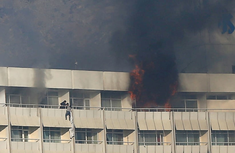 A man tries to escape from a balcony at Kabul's Intercontinental Hotel during an attack by gunmen in Kabul, Afghanistan January 21, 2018 (photo credit: REUTERS/OMAR SOBHANI)