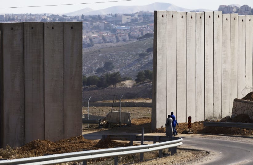 Palestinians walk near an opening in Israel's barrier in the east Jerusalem neighborhood of A-tur January 3, 2014. (photo credit: RONEN ZVULUN / REUTERS)