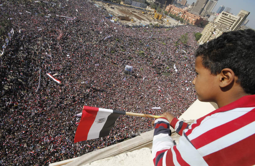 A boy watches as pro-democracy supporters gather in Tahrir Square in Cairo February 18, 2011. (photo credit: REUTERS)