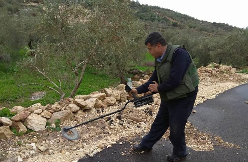 A Palestinian Authority policeman uses a metal detector while searching for explosive devices in the West Bank, January 2018 (photo credit: COURTESY PALESTINIAN AUTHORITY POLICE)