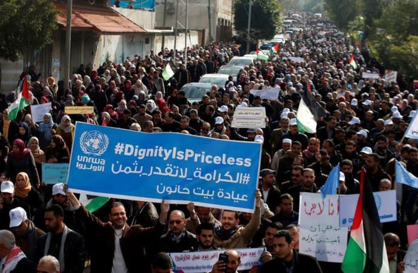 Palestinian employee of United Nations Relief and Works Agency (UNRWA) hold a sign during a protest against a US decision to cut aid, in Gaza City January 29, 2018. (REUTERS/Mohammed Salem) (photo credit: REUTERS/MOHAMMED SALEM)