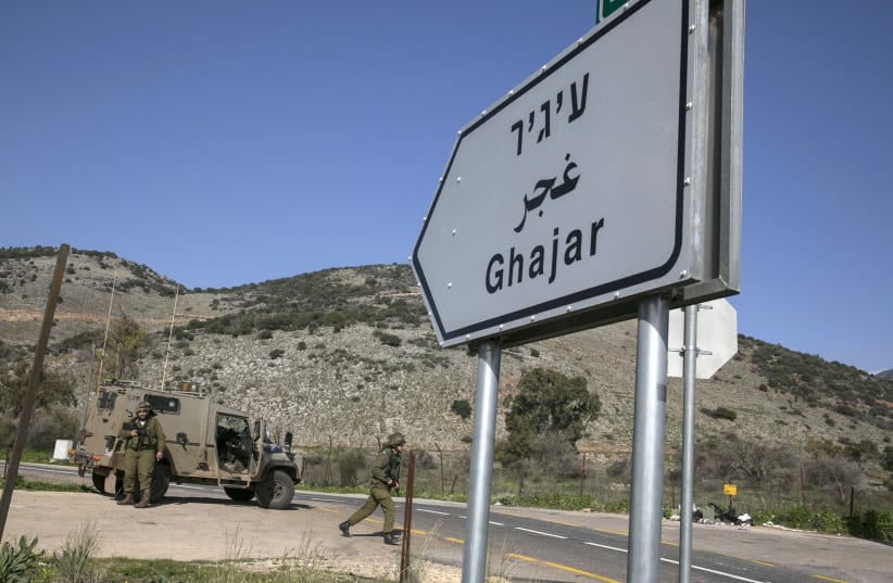 Israeli soldiers are seen next to a sign post pointing to the village of Ghajar near Israel's border with Lebanon (photo credit: BAZ RATNER/REUTERS)