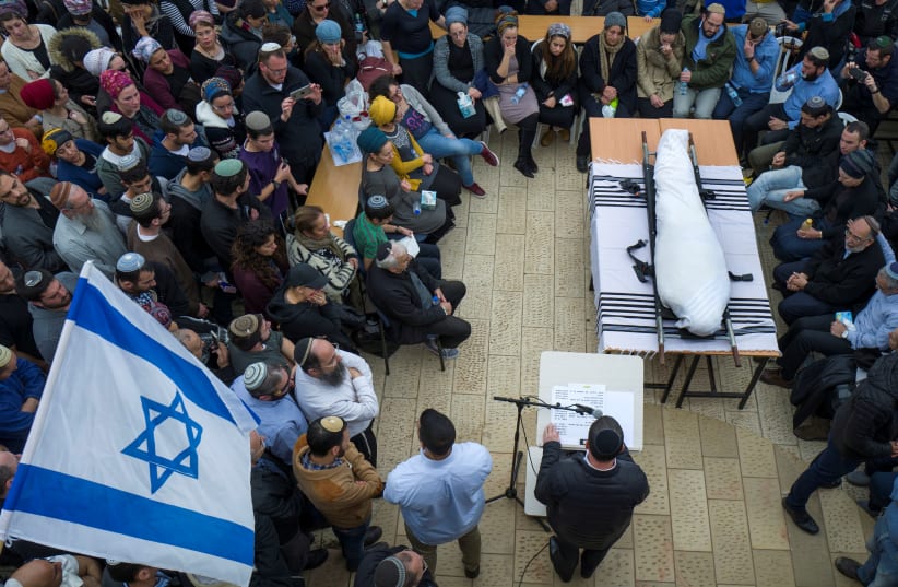 Relatives and friends mourn as they stand around the body of Itamar Ben Gal, an Israeli killed in a stabbing attack on February 5, during his funeral in the Jewish settlement of Har Bracha in the West Bank, February 6, 2018.  (photo credit: REUTERS/JIM HOLLANDER/POOL)