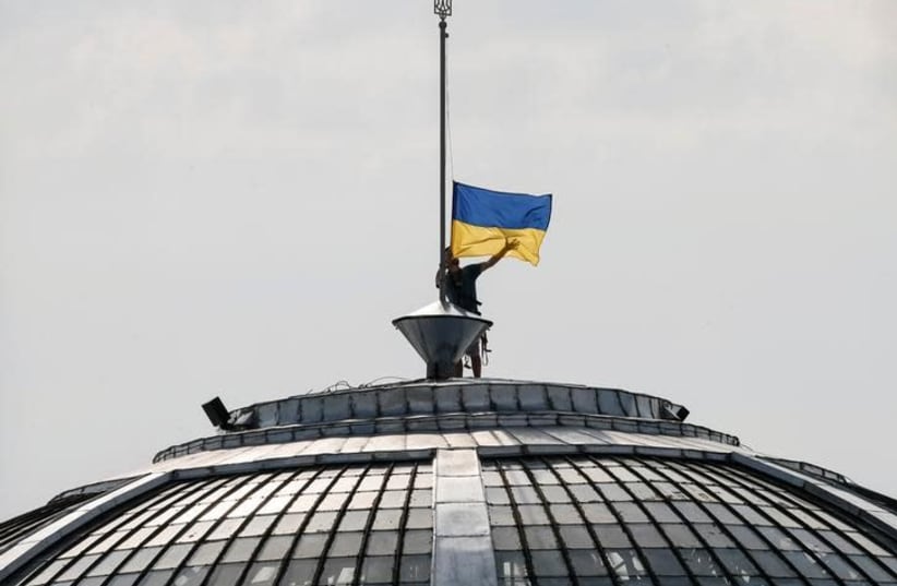 A climber installs the Ukrainian national flag on a roof, marking the Day of the State Flag, on the eve of the Independence Day, in Kiev, Ukraine, August 23, 2016 (photo credit: GLEB GARANICH/REUTERS)