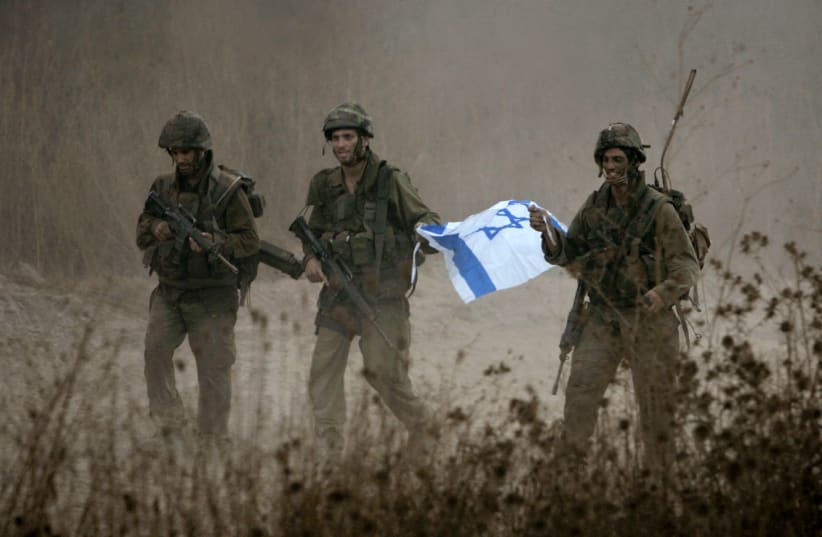 Israeli soldiers hold an Israeli flag as they leave Lebanese territory during a second day of ceasefire during the Second Lebanon War, near the town of Menara August 15, 2006. (photo credit: REUTERS)