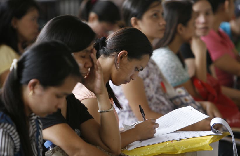 A woman fills an application form for a job posting in Kuwait during a job fair at the Philippine Overseas Employment Agency in Manila in this September 20, 2010 file photo. (photo credit: REUTERS/CHERYL RAVELO/FILES)