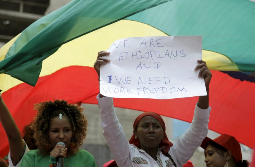 An Ethiopian migrant domestic worker holds up a placard during a parade in Beirut, to support the rights of migrant domestic workers in Lebanon and calling for a domestic workers union in Beirut (photo credit: ALIA HAJU/REUTERS)