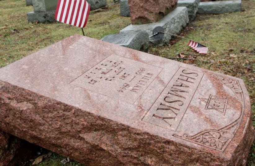 An American flag still stands next to one of over 170 toppled Jewish headstones after a weekend vandalism attack on Chesed Shel Emeth Cemetery in University City, a suburb of St Louis, Missouri, U.S. February 21, 2017. (photo credit: REUTERS/TOM GANNAM)