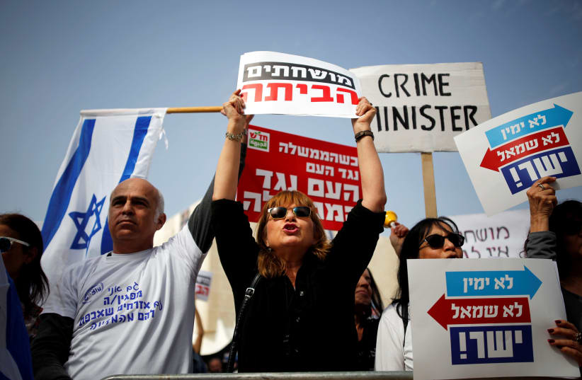 Protesters hold signs as they take part in a rally calling upon Israeli Prime Minister Benjamin Netanyahu to step down in Tel Aviv, Israel February 16, 2018. (photo credit: REUTERS/AMIR COHEN)