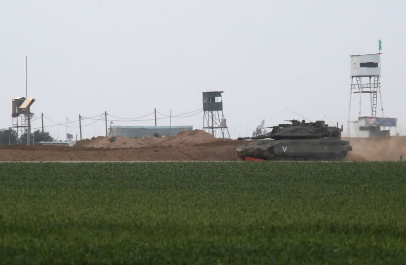 An Israeli tank manoeuvres along the border fence with the southern Gaza Strip, as watch-towers are seen on the Palestinian side near Kibbutz Nirim, Israel February 17, 2018 (photo credit: REUTERS/AMIR COHEN)