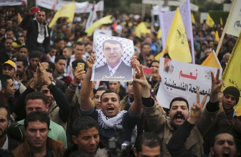 A Palestinian supporter of former head of Fatah in Gaza, Mohammed Dahlan, holds a poster depicting Dahlan during a protest against Palestinian President Mahmoud Abbas in Gaza City December 18, 2014 (photo credit: MOHAMMED SALEM/REUTERS)